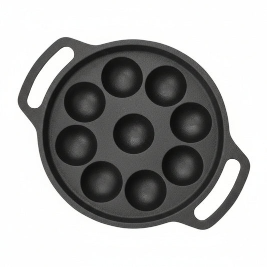 A dark gray cast iron pan with seven deep round domed cavities and two side handles, shown on a plain light gray background.